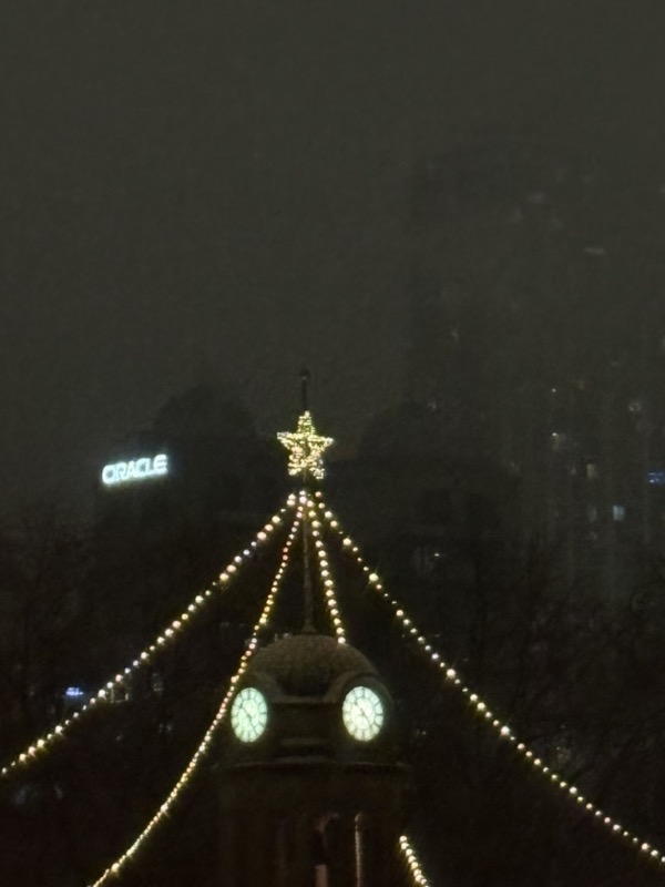 Nighttime photo of the clocktower in Willow River Park, strung up with Christmas lights